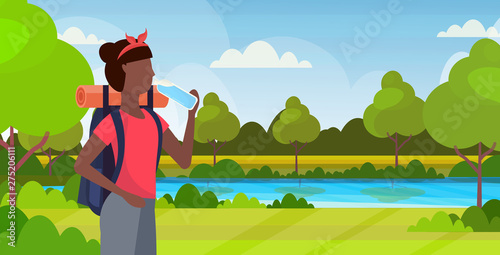 woman hiker with backpack drinking water african american girl traveler on hike hiking concept beautiful nature landscape background portrait flat horizontal