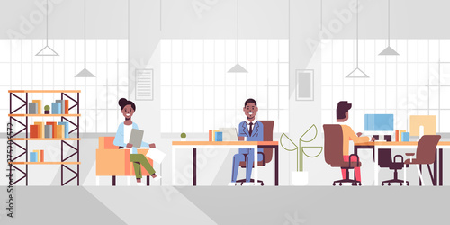 corporate staff employees working in creative co-working open space african american businesspeople sitting at workplace discussing new project modern office interior full length horizontal