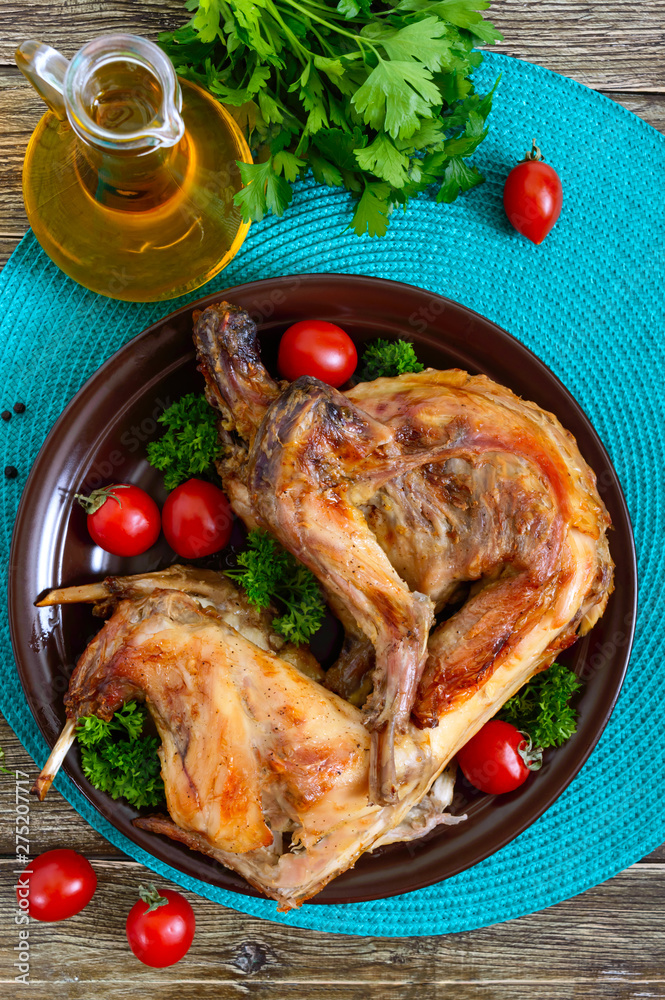 Whole baked rabbit with greens and tomatoes on a plate. Tasty dietary meat. Whole baked rabbit with greens and tomatoes on a plate. Tasty dietary meat.