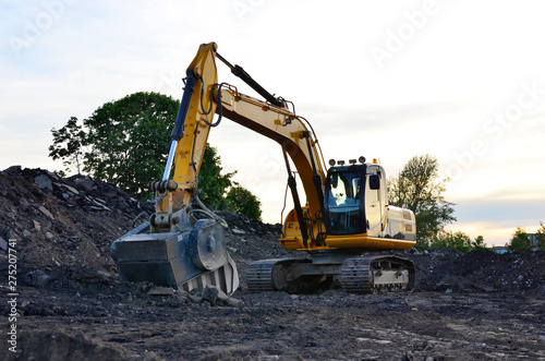 A heavy excavator in a working at granite quarry unloads old concrete stones for crushing and recycling to gravel or cement. Special heavy construction equipment for road construction.