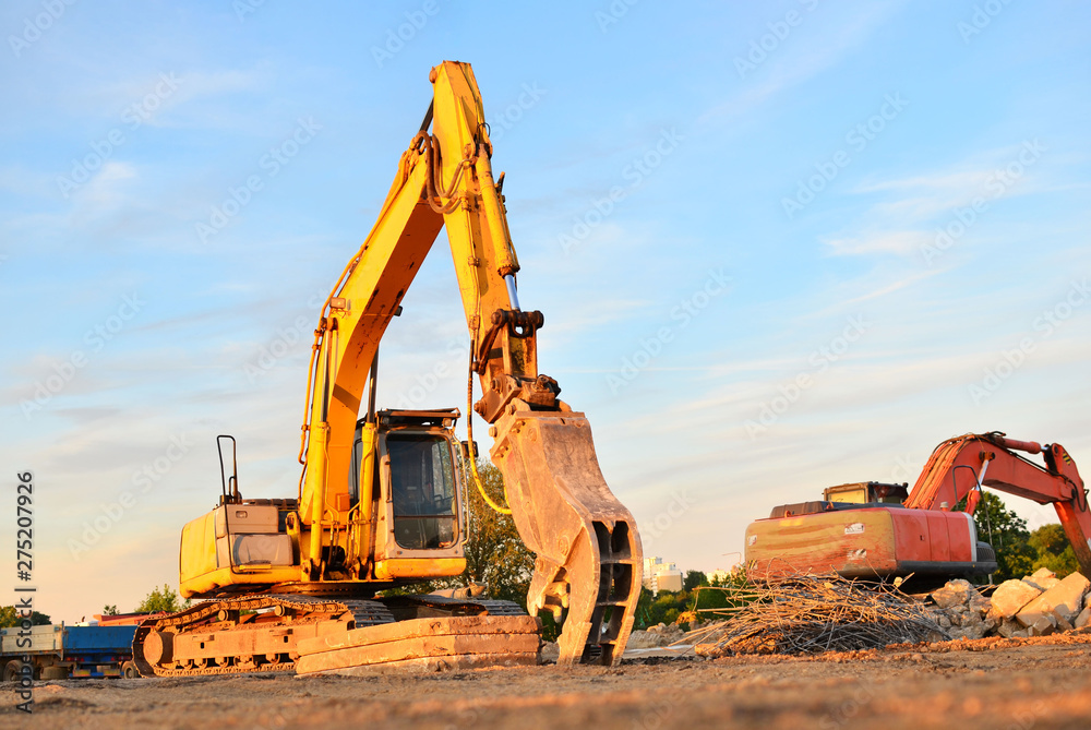 Excavator on a construction site cuts and crumbles old concrete and asphalt. Hydraulic breaker grinder. Crusher for concrete slabs. Hammer crushes breaker concrete piles and reinforcement elements. Excavator on a construction site cuts and crumbles old concrete and asphalt. Hydraulic breaker grinder. Crusher for concrete slabs. Hammer crushes breaker concrete piles and reinforcement elements.