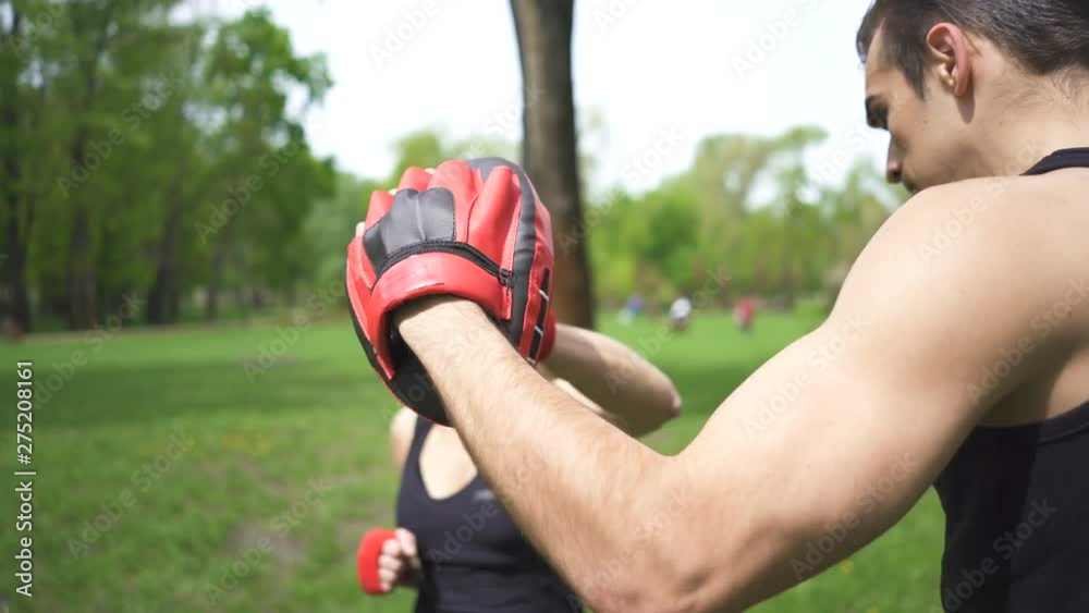 4К. Boxer outdoor training of man and woman with boxing paws. City park ,steady shot 4К. Boxer outdoor training of man and woman with boxing paws. City park ,steady shot
