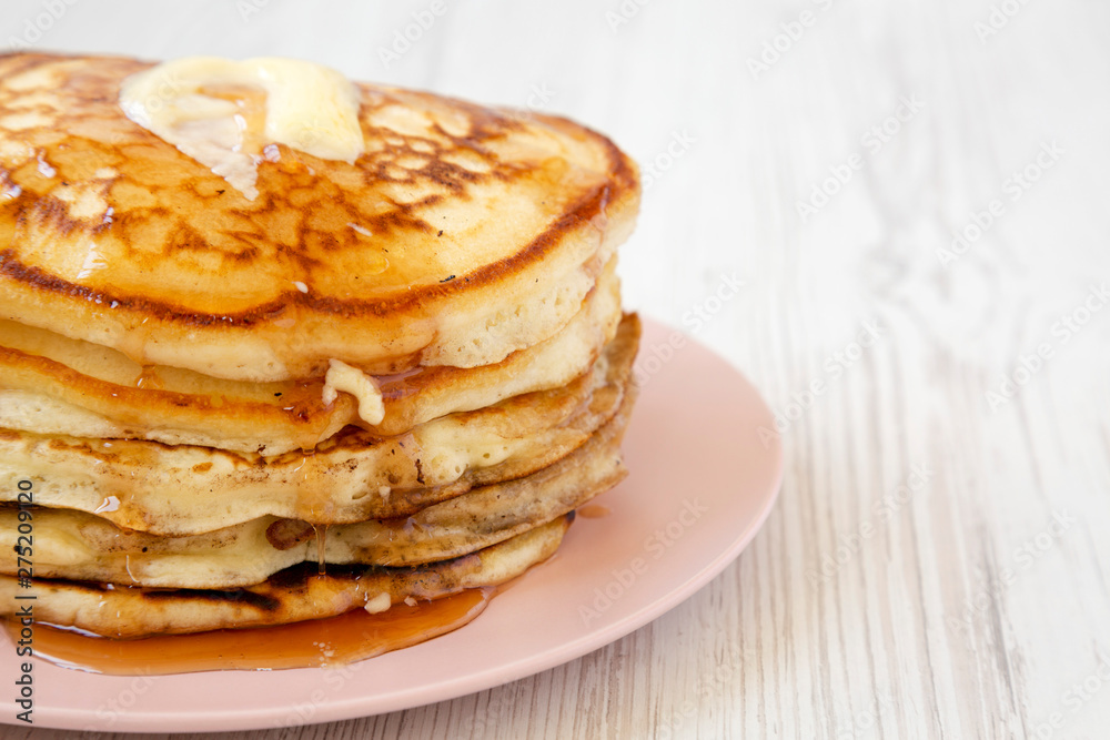 Homemade pancakes with butter and maple syrup on a pink plate, side view. Copy space. Homemade pancakes with butter and maple syrup on a pink plate, side view. Copy space.
