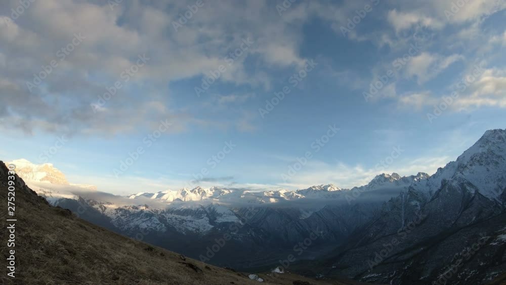 Evening time-lapse of a mountain valley with snow-capped mountain peaks during the twilight of a blue hour at a wide angle Evening time-lapse of a mountain valley with snow-capped mountain peaks during the twilight of a blue hour at a wide angle