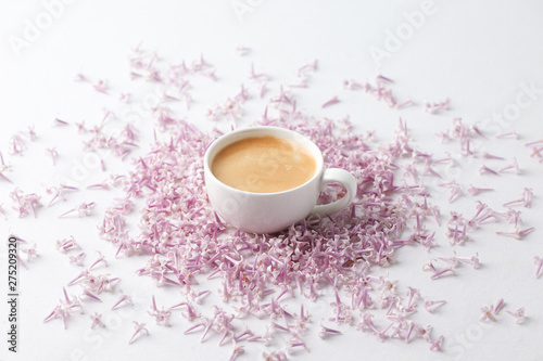 Breakfast in pastel color. Flat lay style with coffee cup and lilac flowers on white background. Top view women background. Minimal concept, wedding, valentine day