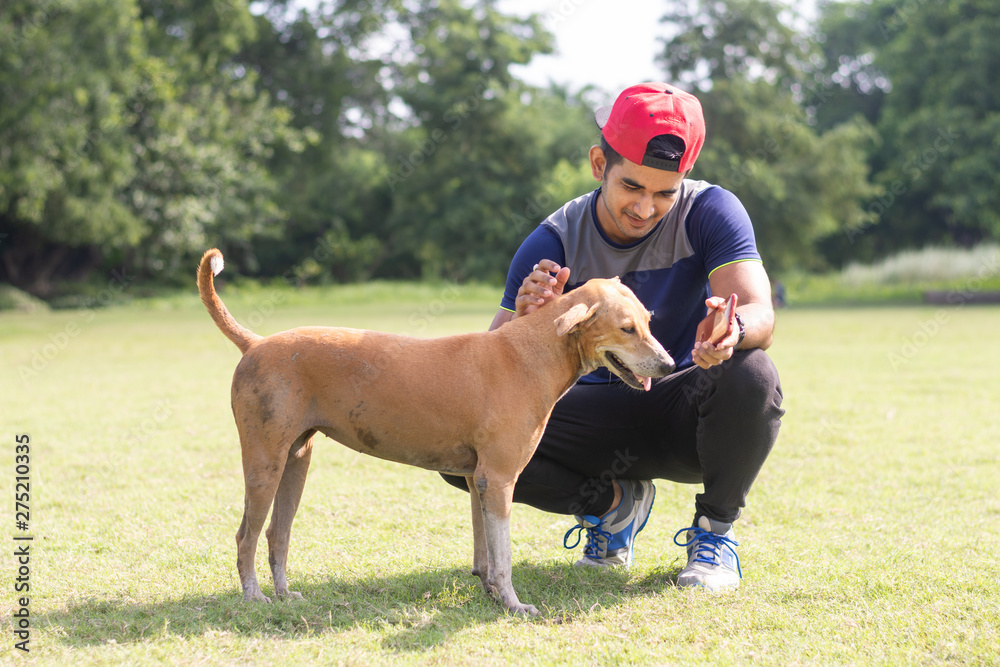 Young Indian sports man playing with dog in sports ground while jogging. Male Sports and fitness concept. Young Indian sports man playing with dog in sports ground while jogging. Male Sports and fitness concept.