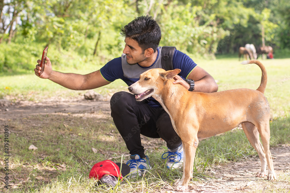 Young Indian sports man playing with dog in sports ground while jogging. Male Sports and fitness concept. Young Indian sports man playing with dog in sports ground while jogging. Male Sports and fitness concept.