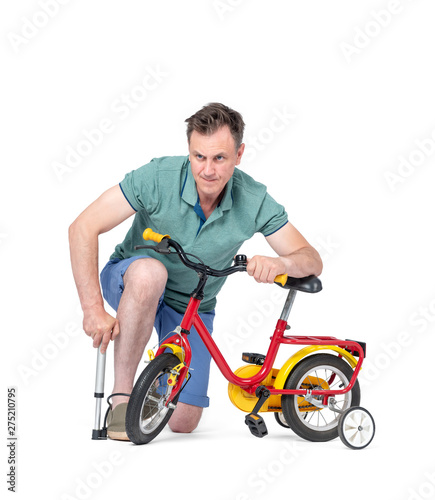 Man in shorts and a t-shirt pumping wheel at children's bike. Isolated on white background.