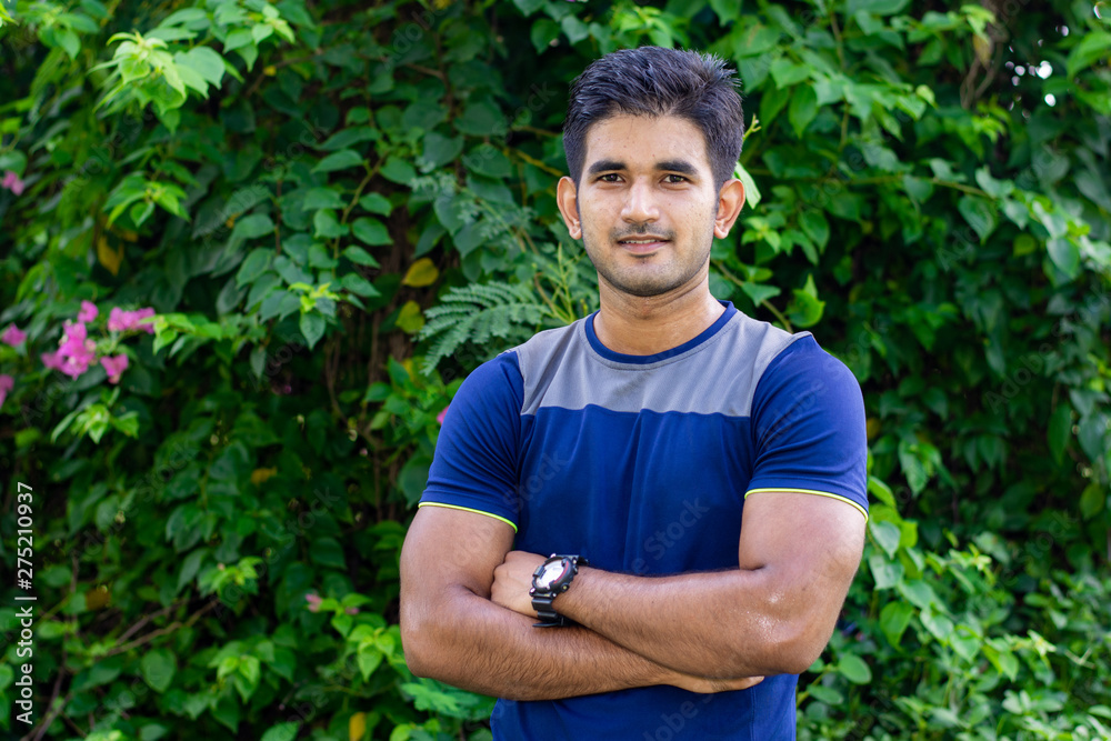 Portrait of young Indian man wearing sports wear and wrist watch in park Portrait of young Indian man wearing sports wear and wrist watch in park