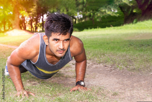 Young fit Caucasian man doing push-ups outdoors on sunny summer day. Fitness and sport lifestyle concept.