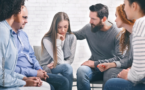 Concerned patients comforting depressed woman in rehab group