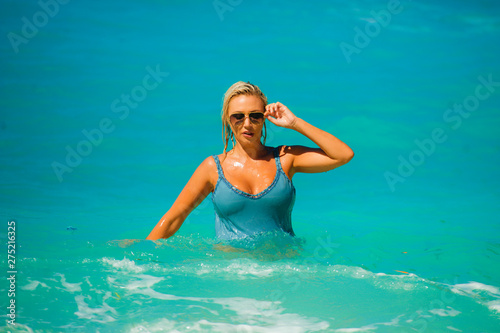 young happy and sexy blond woman in bikini playing with waves in the sea at stunning beautiful tropical beach enjoying carefree summer holidays in travel concept