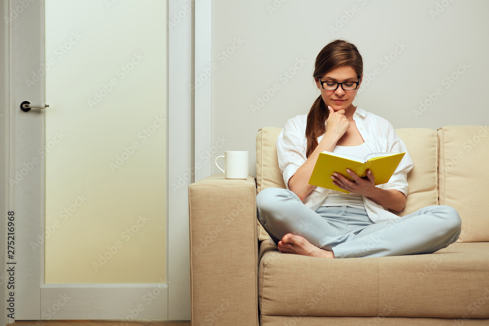 woman wearing glasses sitting on sofa and reading book. woman wearing glasses sitting on sofa and reading book.