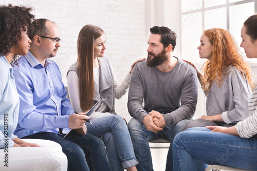 Young women supporting depressed man at therapy meeting