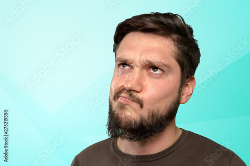 Bearded young man thinking about swomething and looking up