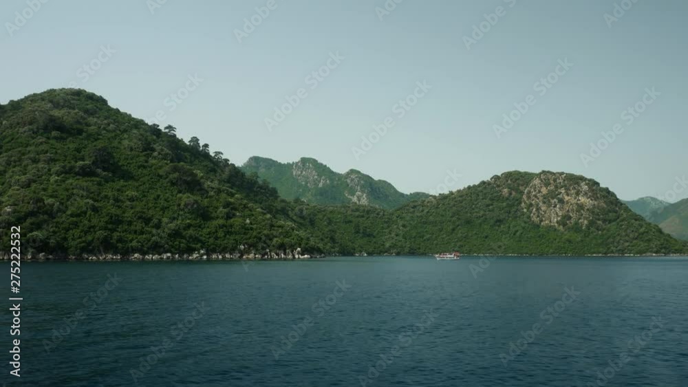 Boat on the horizon next to green hills