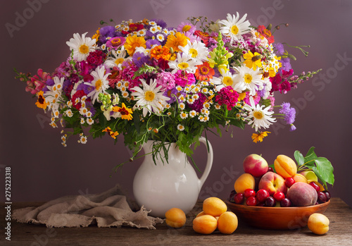 bouquet of summer flowers in a jar and fresh fruits