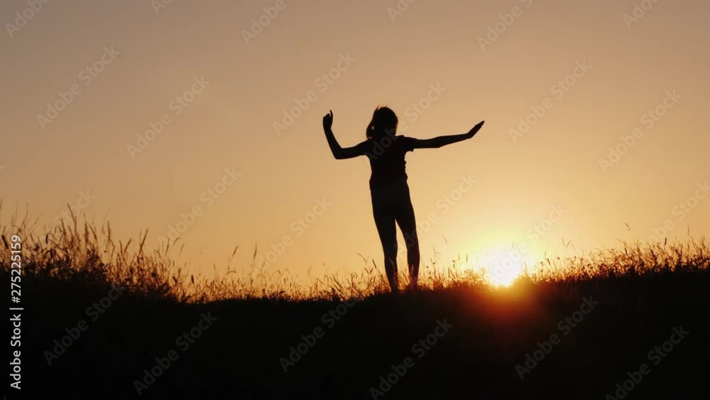 Silhouette of a little girl making acrobatic wheel in a beautiful sunset setting Silhouette of a little girl making acrobatic wheel in a beautiful sunset setting