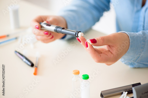 Фотография Woman taking blood sample with lancet pen. Diabetes.