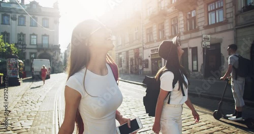 Two trendy young women spending good time in old european city downtown, sightseeing on pleasant summer evening