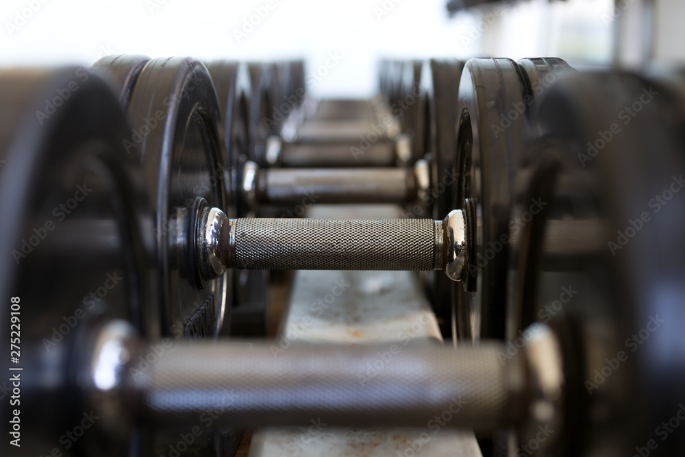 Heavy black metal dumbbells lying in a row, closeup Heavy black metal dumbbells lying in a row, closeup