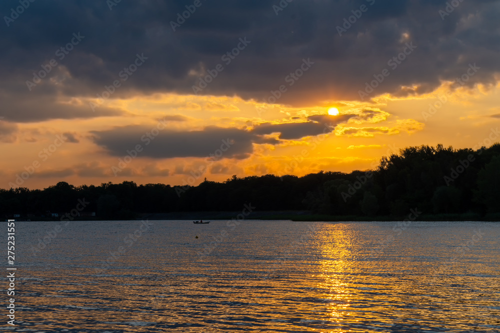 Orange romantic sunset over lake on a beautiful summer evening.