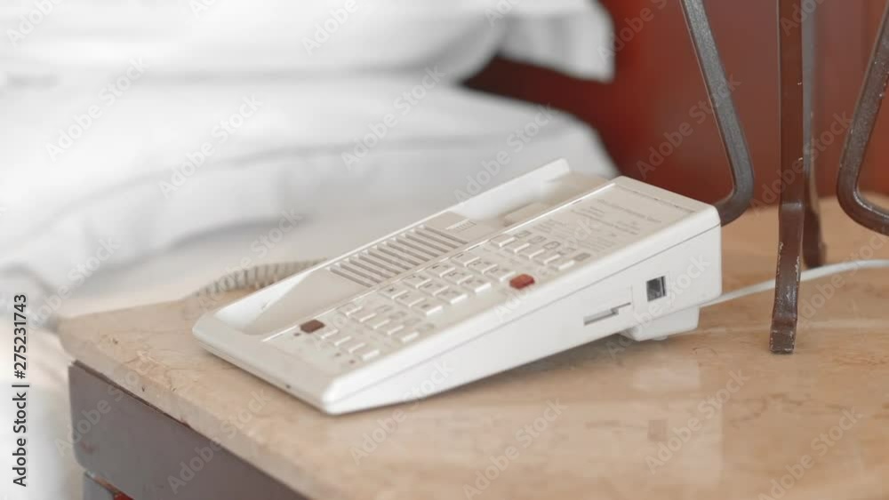 Unrecognized adult senior woman in a white bathrobe picks up the phone in the hotel room and presses the lever. Slow Motion, Close-up.