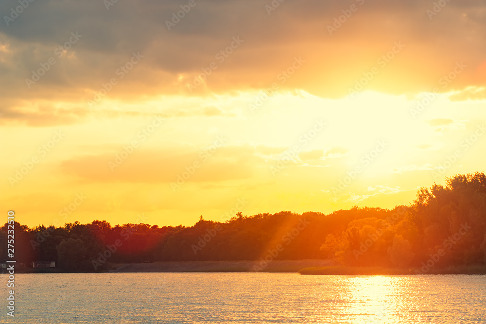 Orange romantic sunset over lake on a beautiful summer evening.