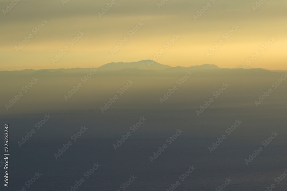 Mountains and the sea, sunset, sky in pastel colors, light haze, blur
