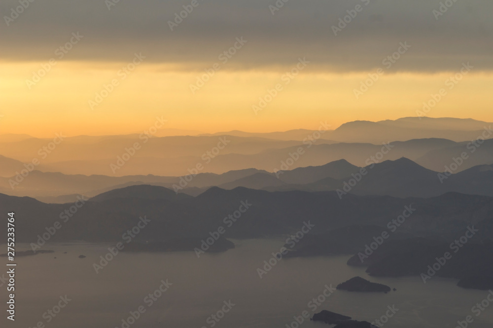 Mountains and the sea, sunset, sky in pastel colors, light haze, blur
