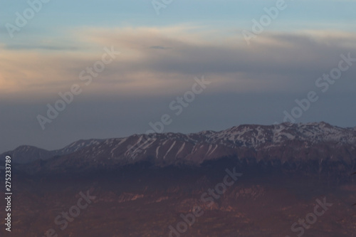 Pink sunset sunning in the mountains, on the tops of the mountains lies snow.