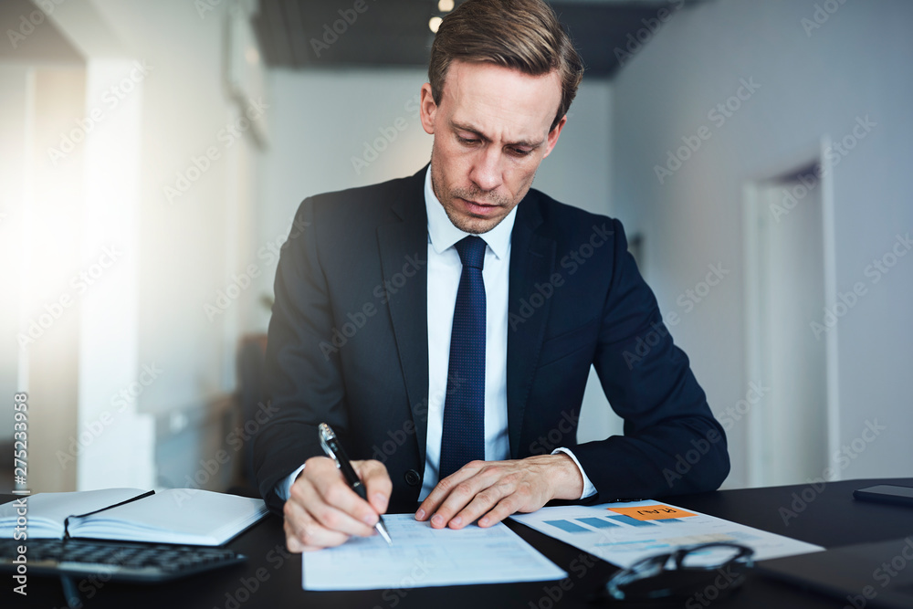 Businessman signing documents while working at his office desk