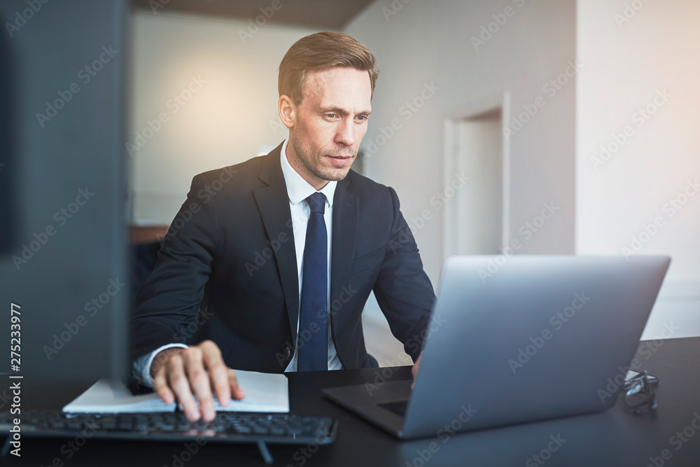 Businessman working online with a laptop at his office desk Businessman working online with a laptop at his office desk