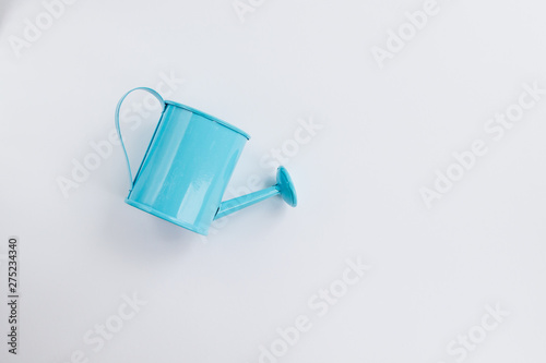 Blue watering can toy on a white background. Place for text. The concept of agriculture. View from top.