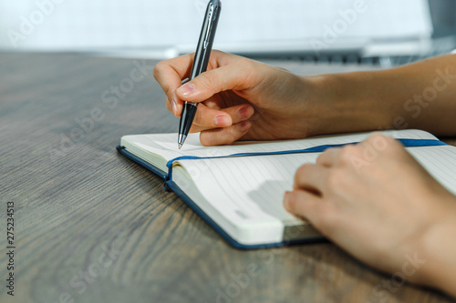 Female hands are writing in a notebook