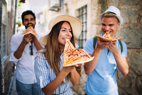 Group of friends eating pizza while traveling on vacation