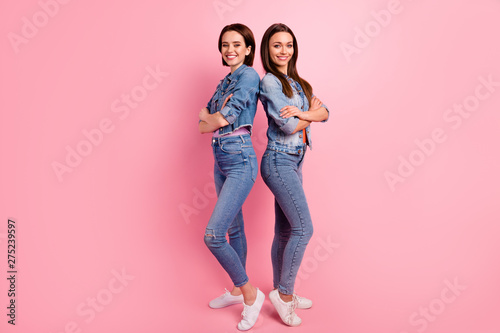 Full length side profile body size photo two beautiful she her ladies cool teamwork unity leaders arms crossed stand back fellowship wear jeans denim jackets blazers isolated bright pink background