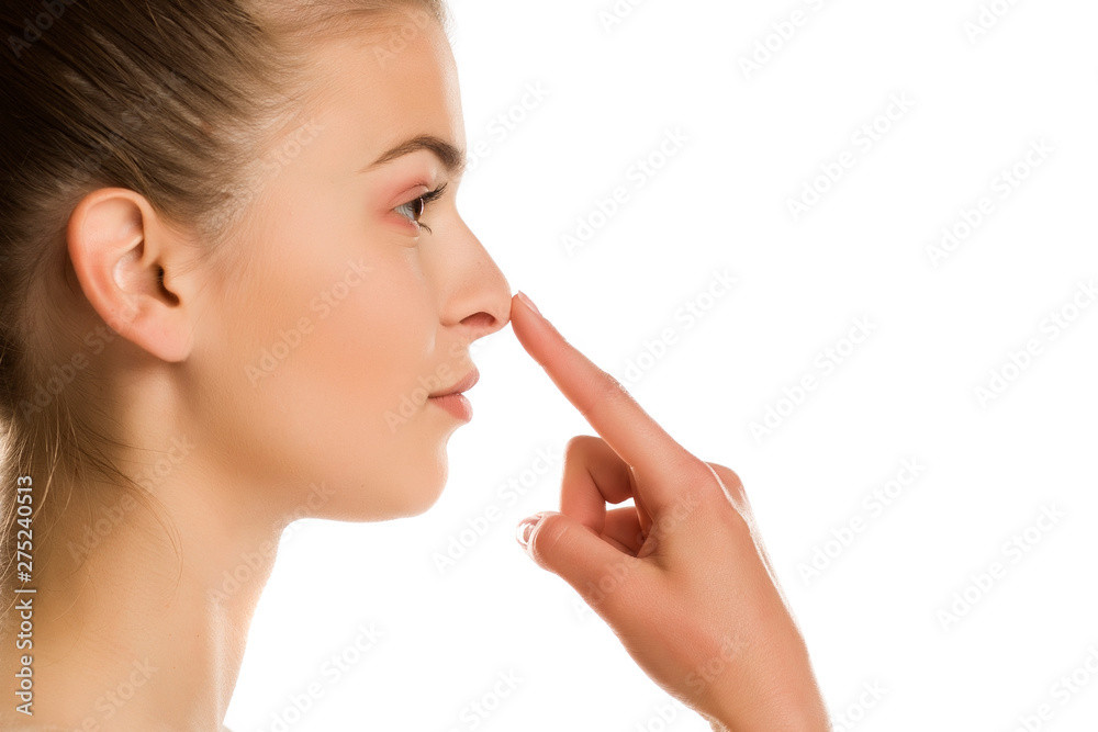 profile of young woman touches her nose on white background profile of young woman touches her nose on white background