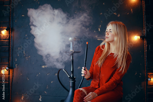 girl smokes hookah / beautiful glamorous girl in red dress smokes a hookah, the sexy model in a night club smokes