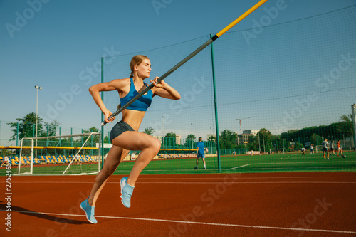 Professional female pole vaulter training at the stadium in sunny day. Fit female model practicing in high jumps outdoors. Concept of sport, activity, healthy lifestyle, action, movement, motion. © master1305