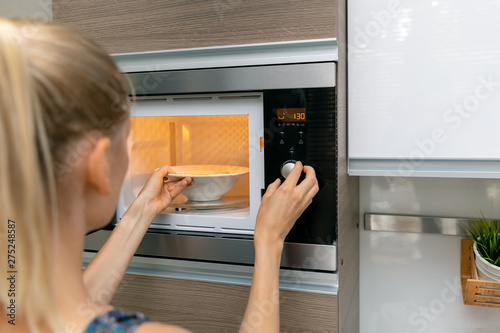 woman warm up the food in microwave oven at home photo