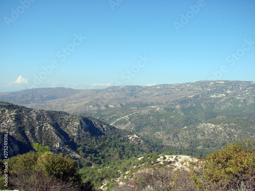The landscape from the top of a mountain of endless mountain ranges covered with green forest on the background of a clean, blue, morning sky on the horizon. © Hennadii