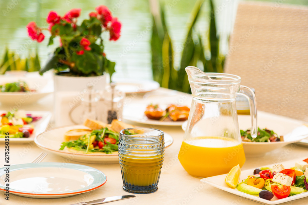 Freshly squeezed orange juice standing near salads Freshly squeezed orange juice standing near salads