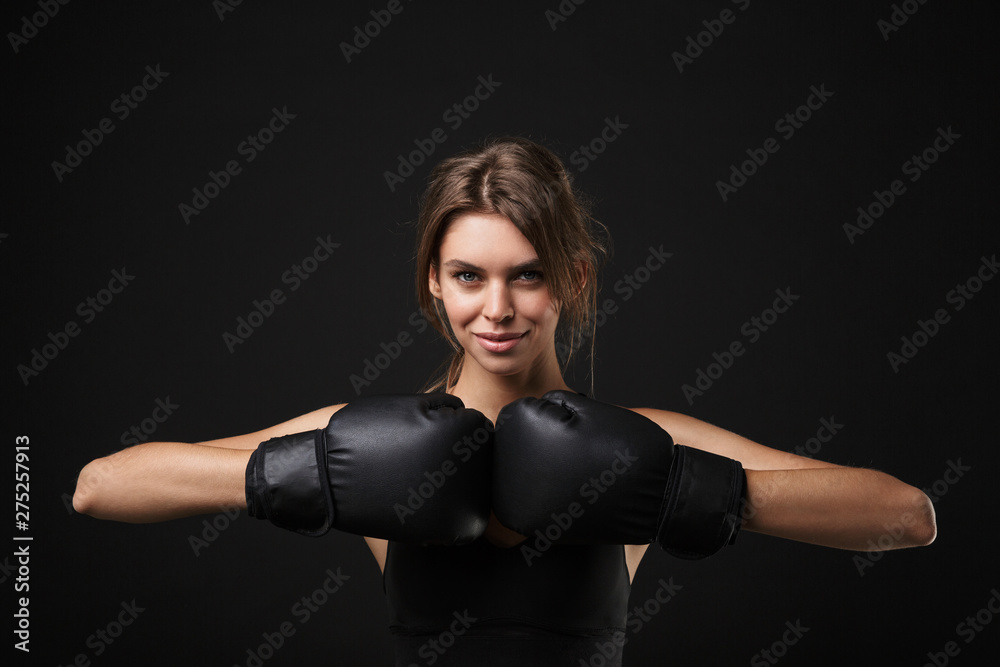 Portrait of athletic caucasian woman in sportswear posing at camera with boxing gloves during workout in gym