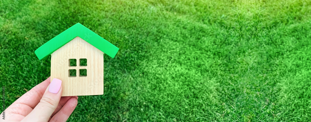 Miniature wooden house on green grass. Real estate concept. Eco-friendly and energy efficient house. Buying a home outside the city. The urban downshift. Nature. Fresh air. Mortgage, loan. Property Miniature wooden house on green grass. Real estate concept. Eco-friendly and energy efficient house. Buying a home outside the city. The urban downshift. Nature. Fresh air. Mortgage, loan. Property