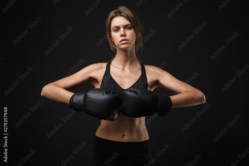 Portrait of tense caucasian woman in sportswear posing at camera with boxing gloves during workout in gym Portrait of tense caucasian woman in sportswear posing at camera with boxing gloves during workout in gym