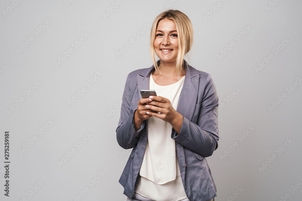 Amazing happy young pretty woman posing isolated over grey wall background using mobile phone. Amazing happy young pretty woman posing isolated over grey wall background using mobile phone.