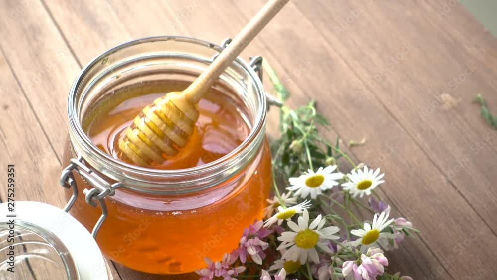 Pot Of Honey And Wooden Stick Are On A Table outdoors. Pot Of Honey And Wooden Stick Are On A Table outdoors.