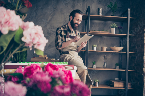 Portrait of his he nice attractive cheery cheerful glad guy gardener using digital e-book browsing at modern industrial loft concrete style indoors workplace photo