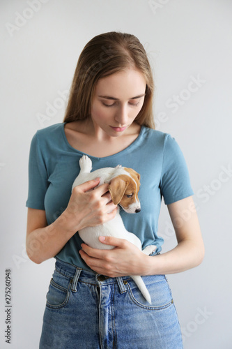 Young beautiful woman holding and playing with the cuttest two months old Jack Russel terrier puppy named Maisie. Small adorable doggy with funny fur stains. Close up, copy space, isolated background. photo